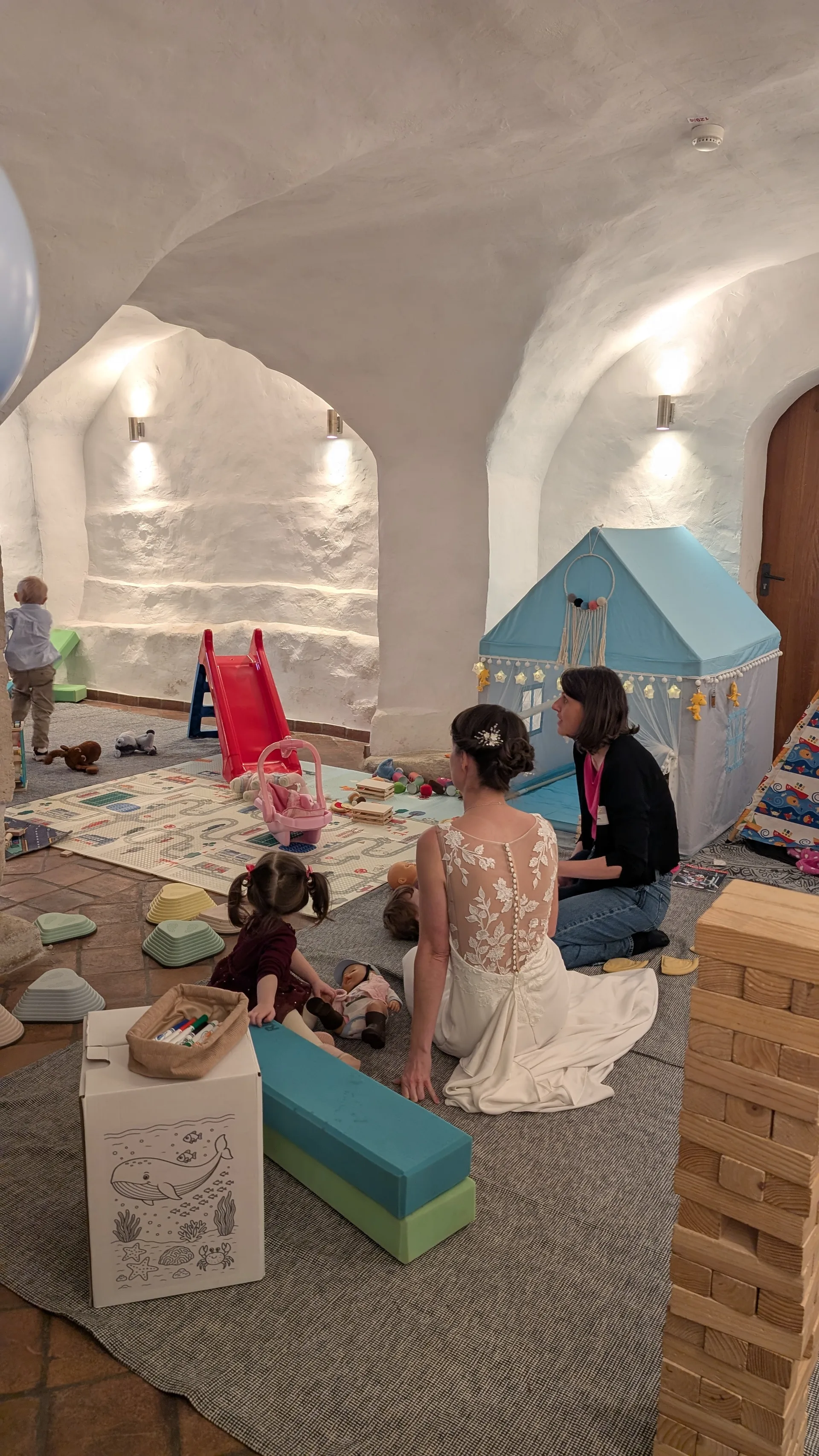 Die Braut, ein Gast und Kinder spielen gemeinsam im Kinderbereich