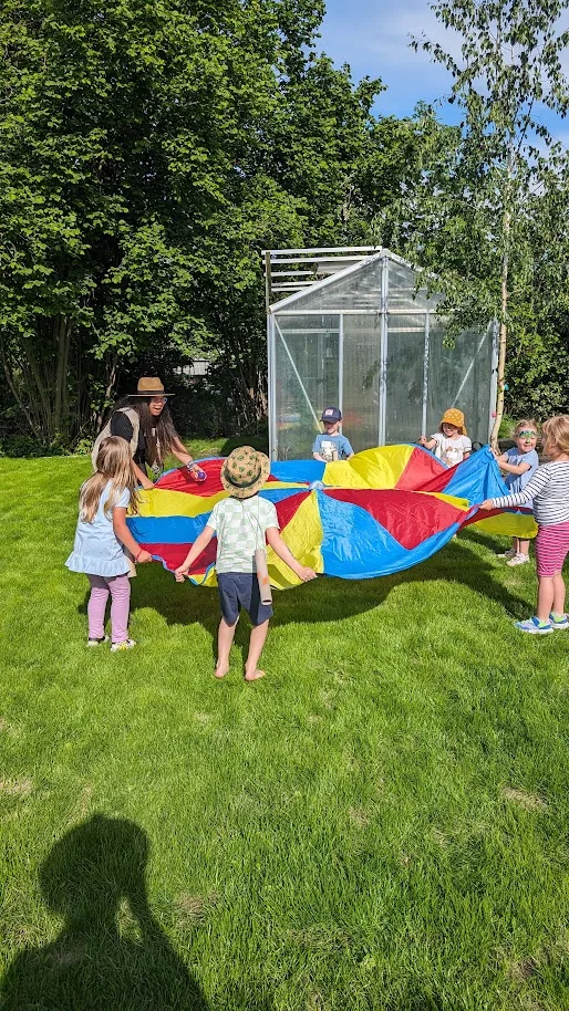 Kinder bewegen sich gemeinsam mit einem großen Schwungtuch als Bewegungs- und Kennenlernangebot